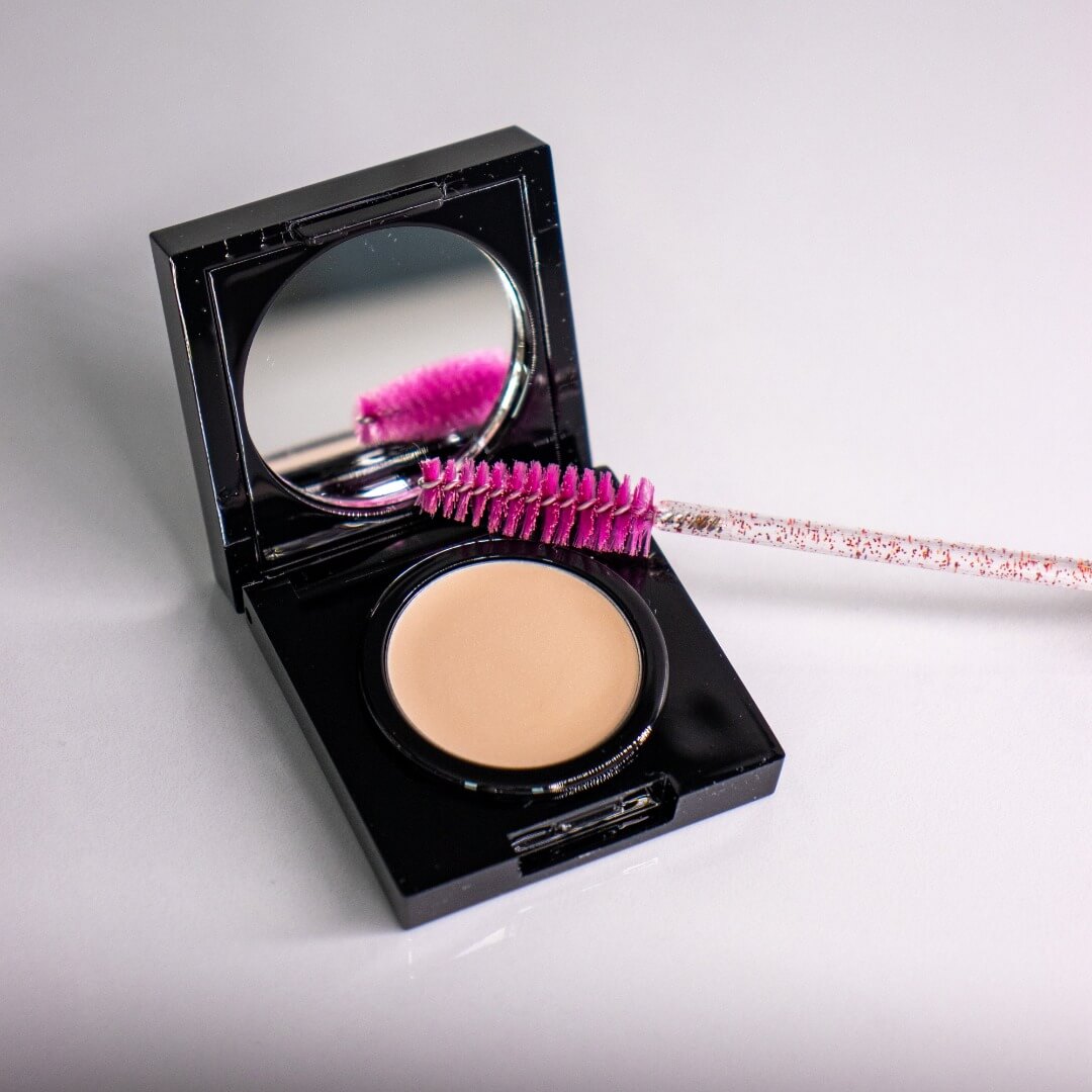 Cire à sourcils dans son boîtier noir et son miroir